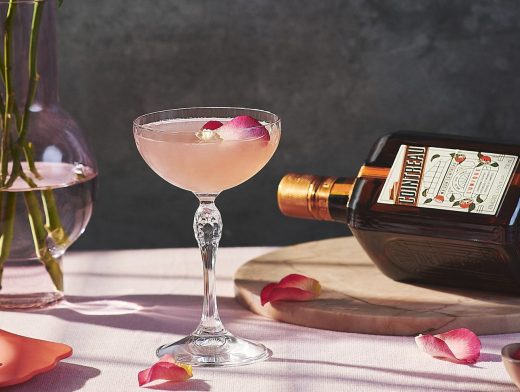 Cointreau Rosé Margarita in coupe glass with flowers and bottle of cointreau