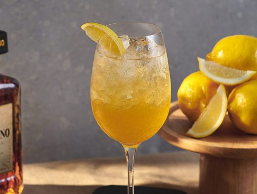 Disaronno Fizz in glass with lemons and disaronno bottle