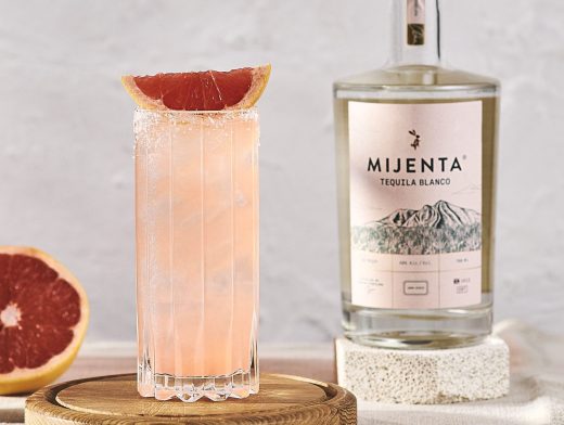 Mijenta Paloma in tall glass with grapefruit garnish and mijenta bottle