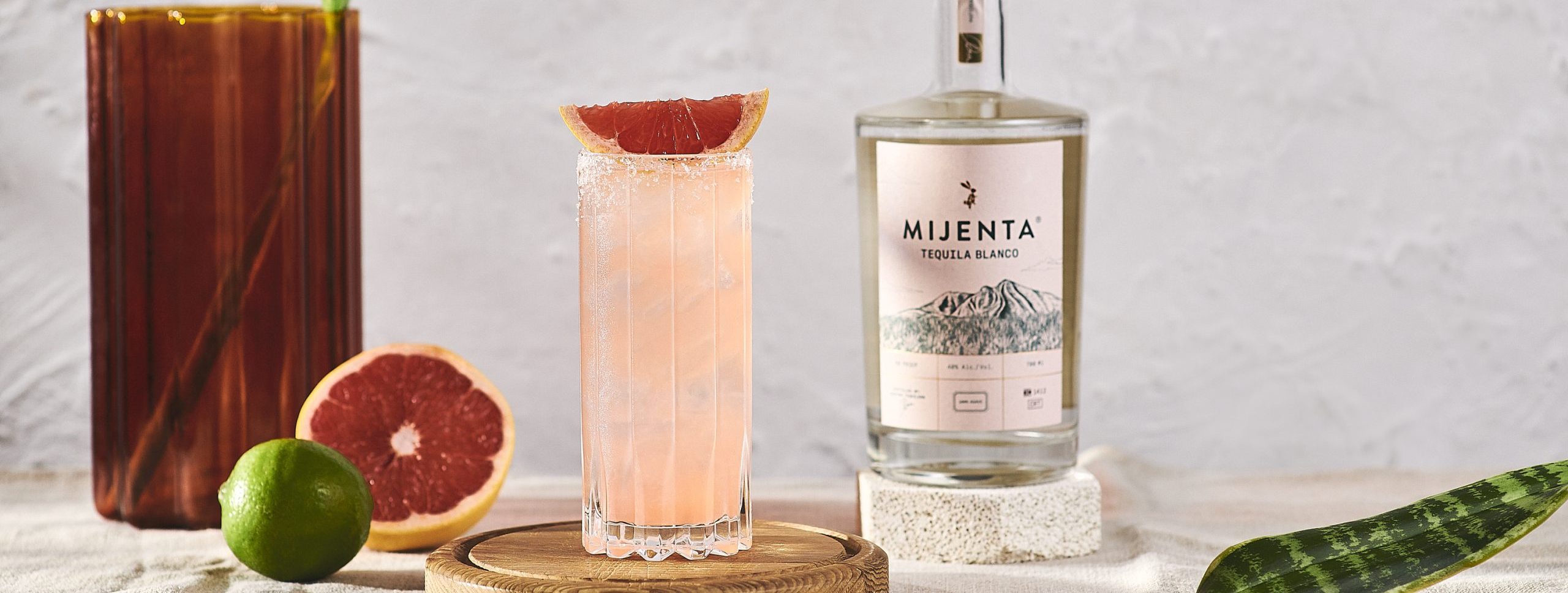 Mijenta Paloma in tall glass with grapefruit garnish and mijenta bottle
