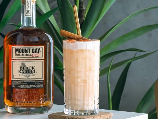 Mount Gay Cinna Coco Colada in highball glass with garnish and bottle of Mount Gay Rum