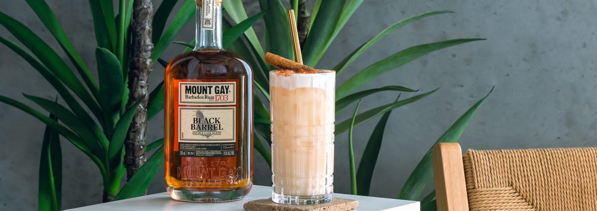 Mount Gay Cinna Coco Colada in highball glass with garnish and bottle of Mount Gay Rum