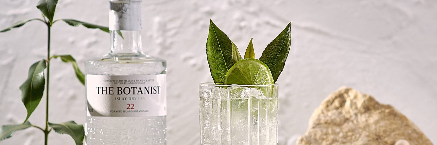 The Botanist Lemon Myrtle B & T in a highball glass with a bottle of the Botanist Gin Bottle