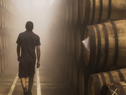Distillery worker walking through an aisle of whisky barrels at The Macallan Distillery