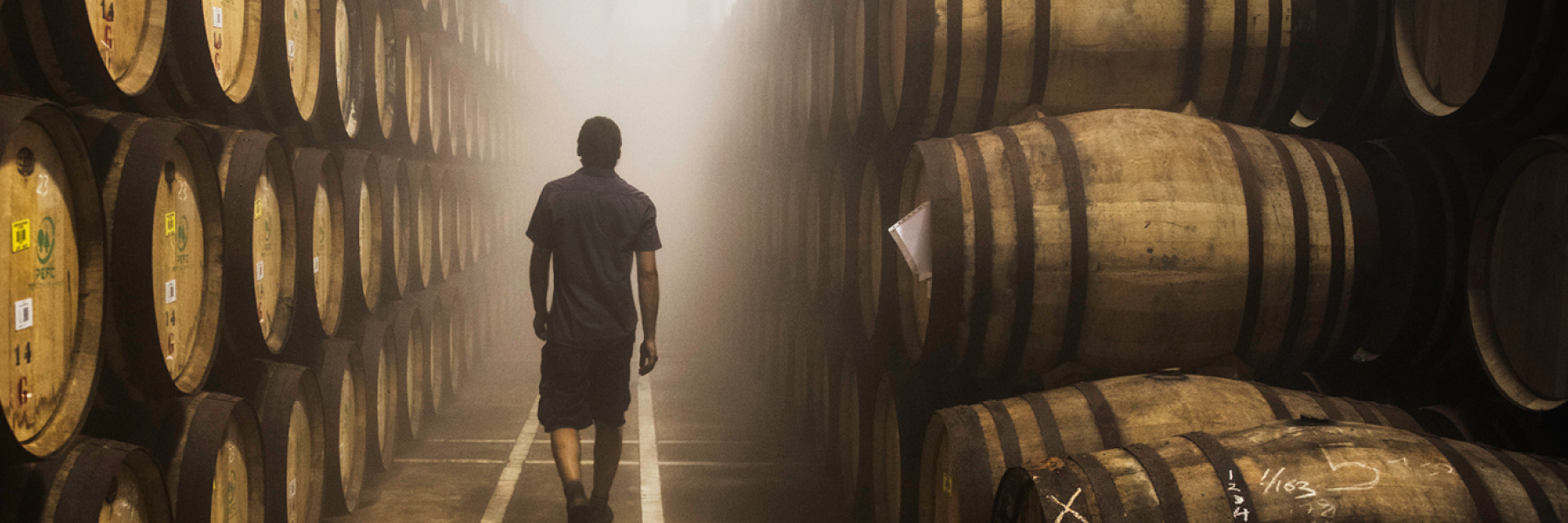 Distillery worker walking through an aisle of whisky barrels at The Macallan Distillery