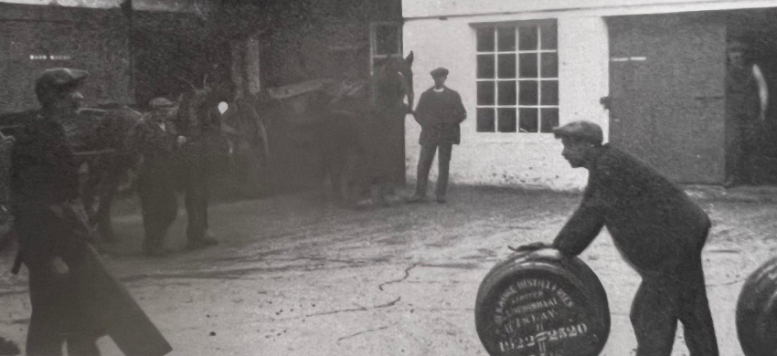 Vintage photograph of distillery worker rolling a barrel at the lochindaal distillery in scotland